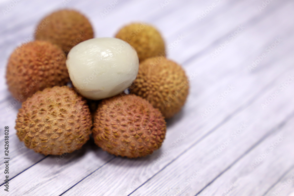 Ripe lychees on a wooden table, peeled and unpeeled. Fresh harvest of exotic fruit lychee