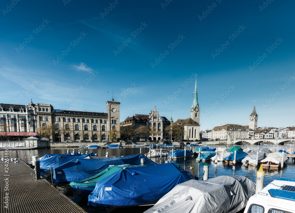 Zurich, ZH / Switzerland - 4 January 2019: boats docked and covered on the Limmat in winter with the cityscape of Zurich behind