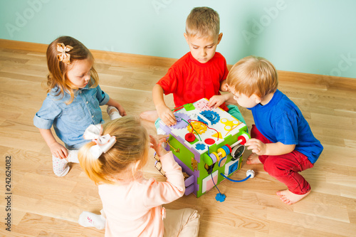 Kindergarten kids playing with educating toy on a wooden floor photo