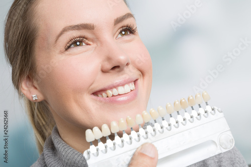Bei einer jungen Frau wird die Zahnfarbe mit einer Zanfarbprobe ermittelt