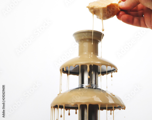 Chocolate fountain of condensed milk, isolated on white background. Delicious Fondue Dessert