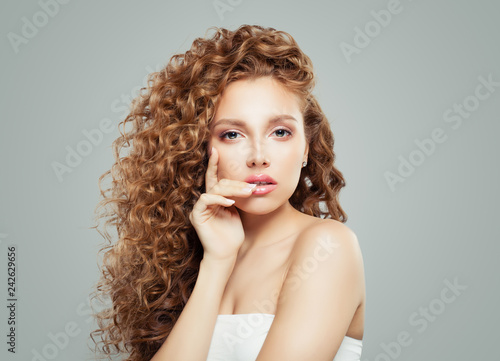 Sensual woman with long healthy wavy hair on gray background