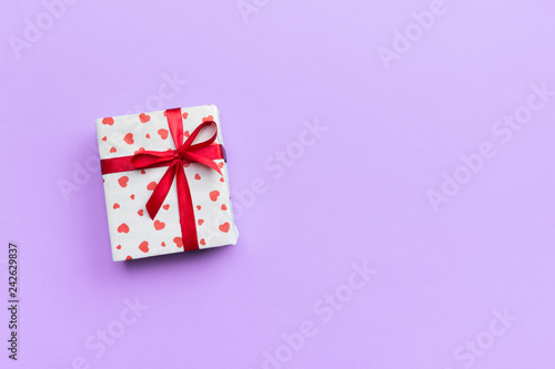 Valentine or other holiday handmade present in paper with red hearts and gifts box in holiday wrapper. Present box of gift on violet colored table top view with copy space, empty space for design © sosiukin