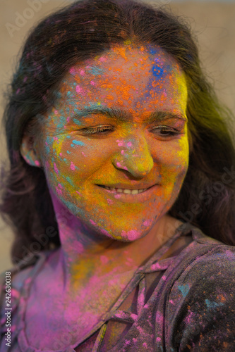 Stunning brunette woman with wavy hair covered with colorful dry paint Holi at the desert