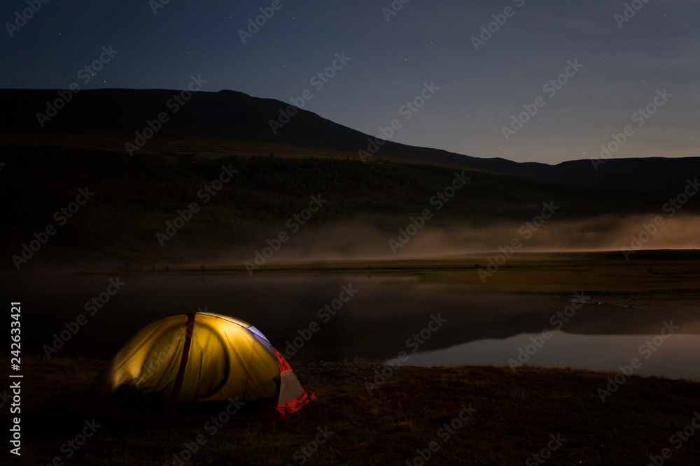 Tourist tent on the shore of the lake at night