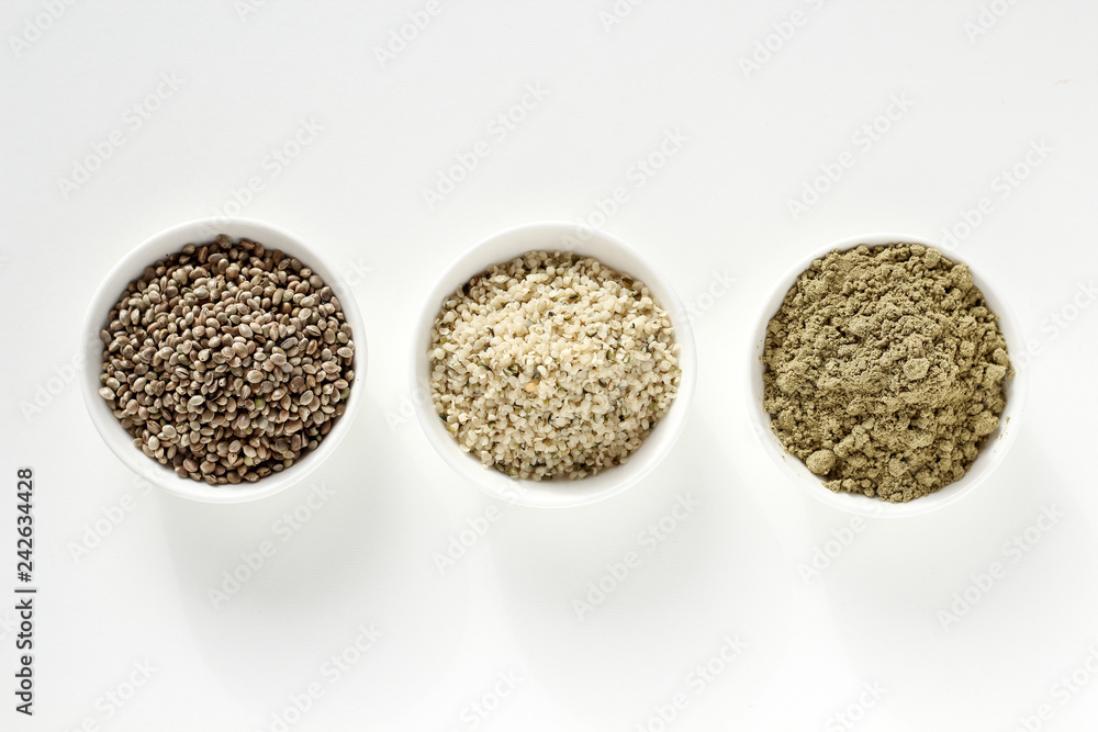 Organic hemp whole seeds, hulled seeds and protein powder in bowls on a white background Organic hemp whole seeds, hulled seeds and protein powder in bowls on a white background