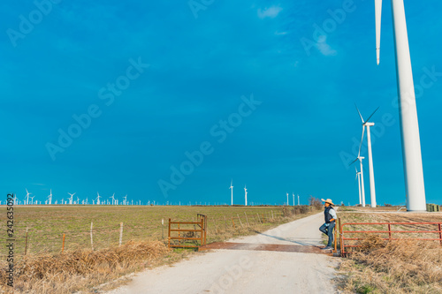 A cowboy standing in front of the wind turbines 