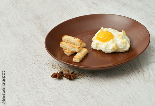 Orsini egg and croutons on a brown plate.