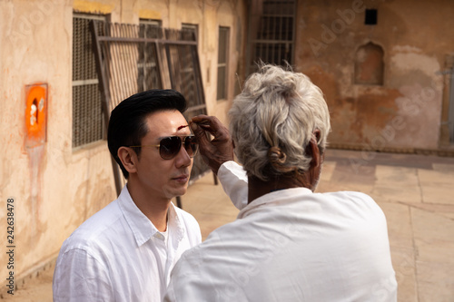 Indian man drawing a dot on tourist forehead on vacation india culture. photo