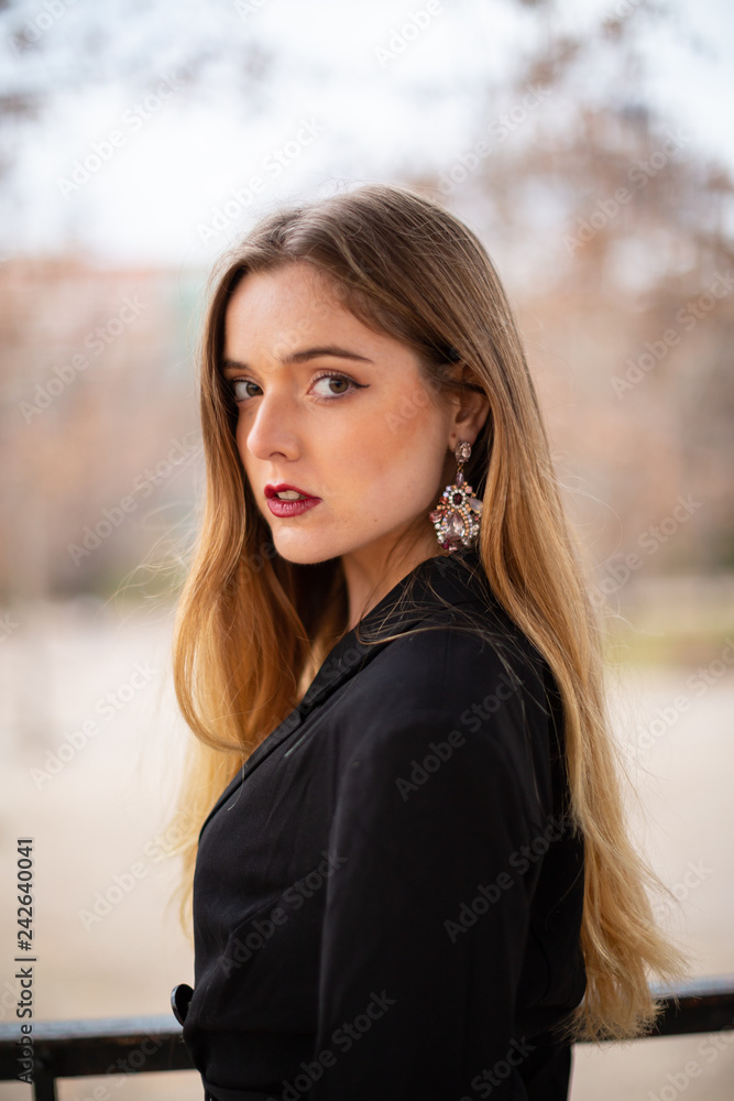 Portrait of pretty model woman posing in a park resting on a fence in autumn Portrait of pretty model woman posing in a park resting on a fence in autumn