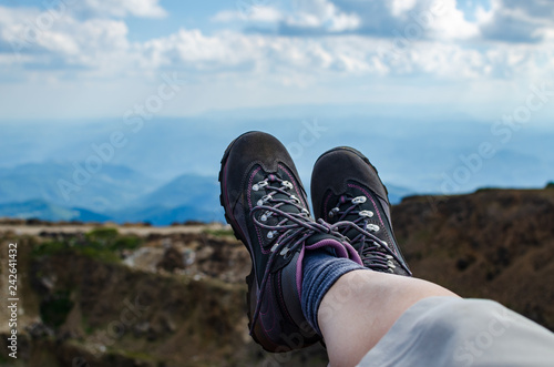 Legs in trekking shoes resting on a mountain field