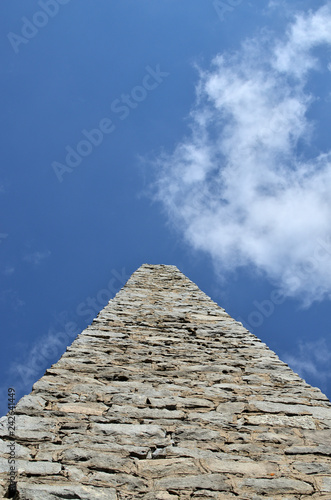 Stone obelisk against blue sky with a cloud