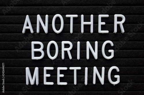 The words Another Boring Meeting in white plastic letters on a black letter board as a reminder to business