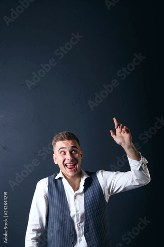 Portrait of young handsome man wearing white shirt standing on the gray background, laughing and raised thumbs up