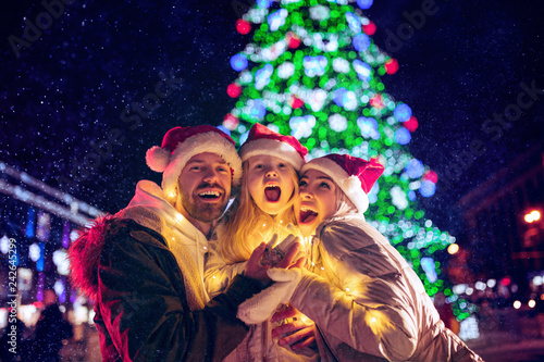 family, christmas, holidays, season and people concept - happy family over lights city background and snow at night