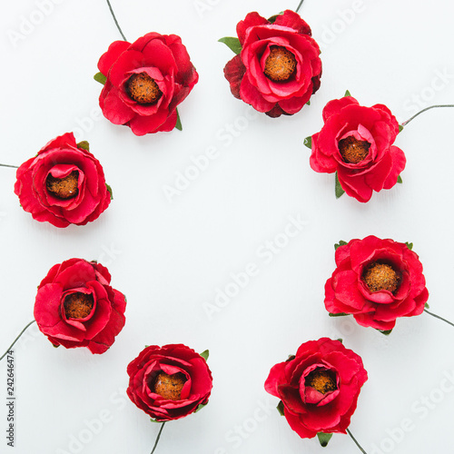 Round frame of paper red flowers on white background. Top view  flat lay.