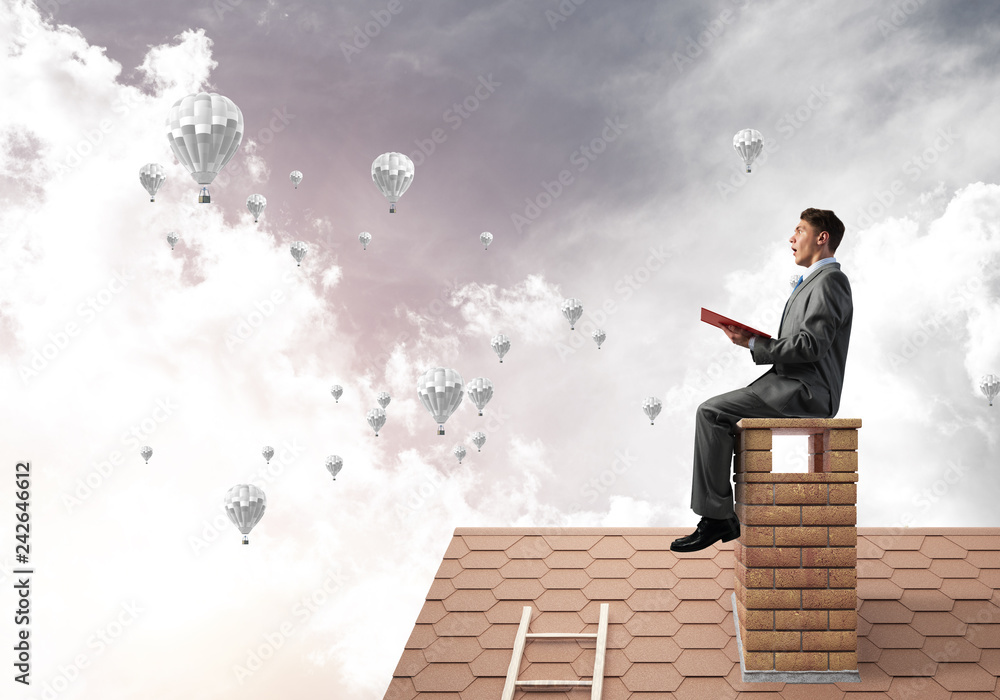 Man on roof reading book and aerostats flying in air Man on roof reading book and aerostats flying in air