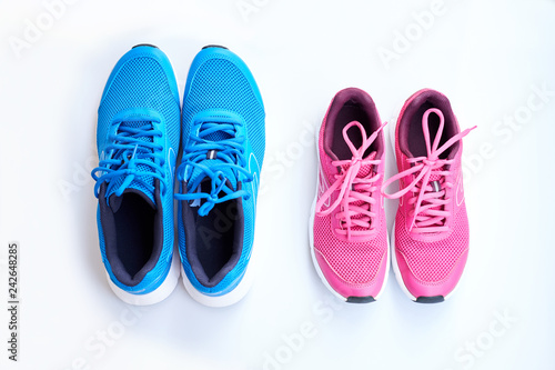 Pair of men's blue sneakers and pair of women's pink sneakers on white background.