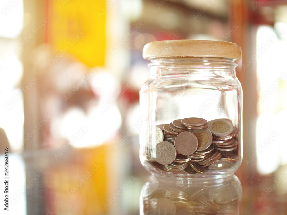 Glass bottle jar contain lot of coins money saving on mirror table Glass bottle jar contain lot of coins money saving on mirror table