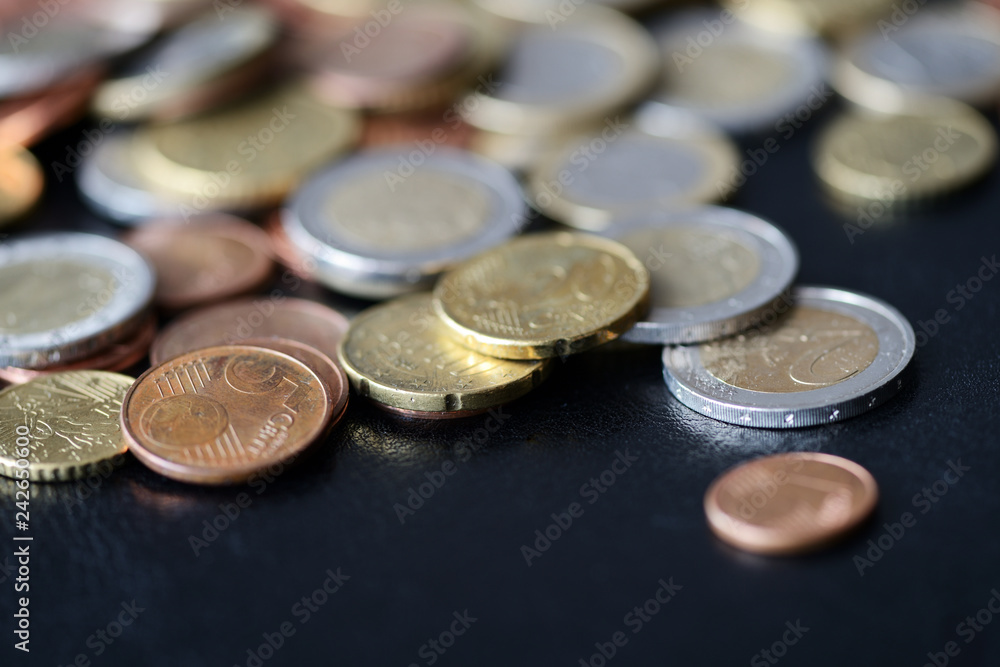 A pile of euro coins scattered on a dark surface close up A pile of euro coins scattered on a dark surface close up