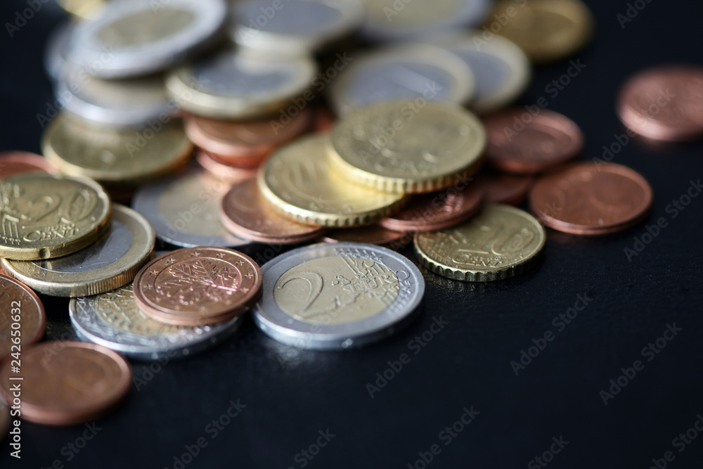 A pile of euro coins scattered on a dark surface close up A pile of euro coins scattered on a dark surface close up