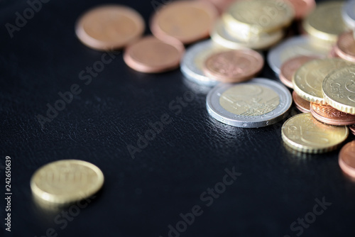 A pile of euro coins scattered on a dark surface close up