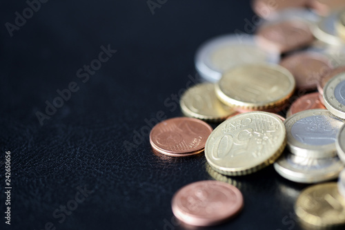 A pile of euro coins scattered on a dark surface close up