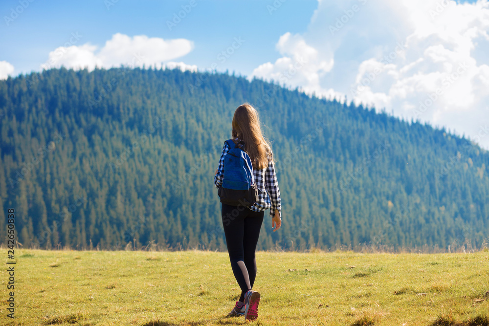 Back view young woman with backpack on top of mountains looking to nature