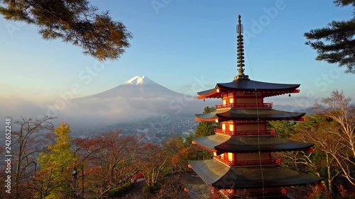 Slow pan of Chureito Pagoda framed on the right side with the backdrop of Mt. Fuji and clear blue sky photo