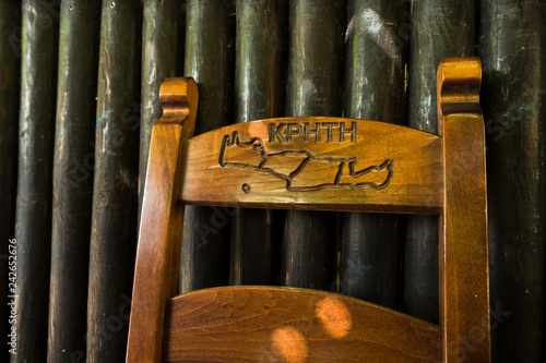 Old wooden chair at morning sunlight in front of taverna wooden wall at the end of Imbros gorge, near Chora Sfakion, island of Crete, Greece photo