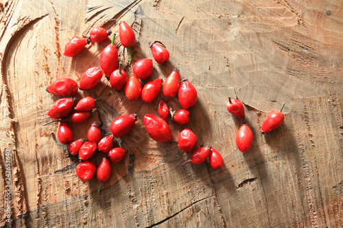 Pile of fresh ripe rosehip on a wooden board. Vitaminic wild red fruits.