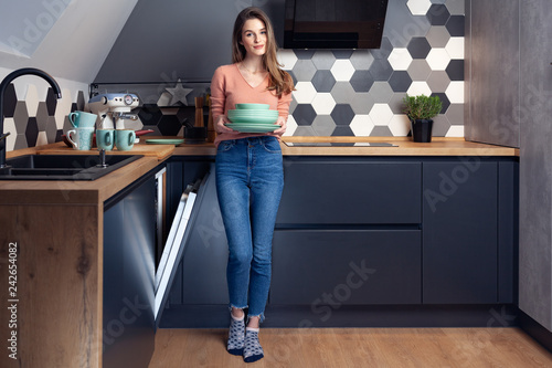 Obraz na plátně Beautiful young woman doing dishes in the kitchen