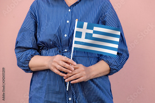 Fototapeta Naklejka Na Ścianę i Meble -  Greece flag. Close up of woman's hands holding Greek flag.