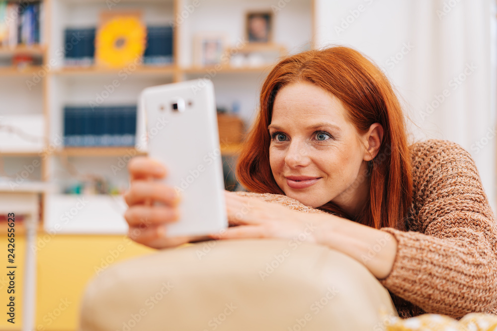Young redhead woman reading a mobile phone message Young redhead woman reading a mobile phone message
