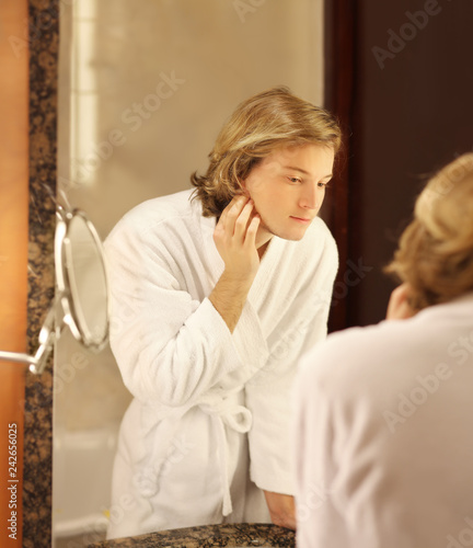 Applying the cream.young man looking in the mirror and combing his hair