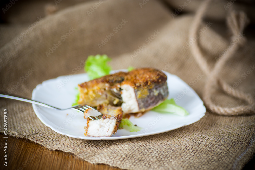 piece of fried pike fish in a plate on a wooden