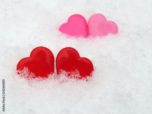 Valentine hearts in the snow, red and pink symbols of love. Background for romantic greeting card, winter wedding