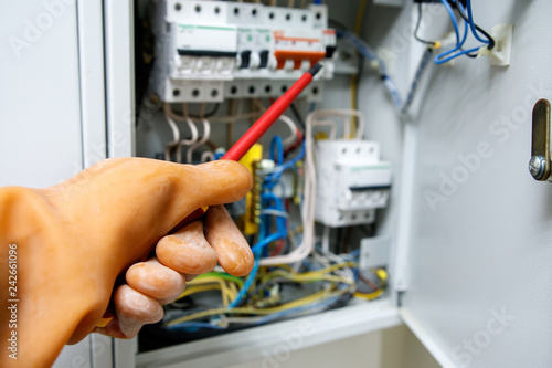 safe operation in electrical installations with rubber glove on hand, red screwdriver on blurred background