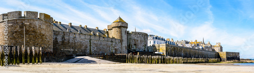 Photo Panoramic view of the surrounding wall of the castle of Duchess Anne of Brittany and old town of Saint-Malo, France, seen from the beach on a sunny morning with the porte Saint-Thomas in the center