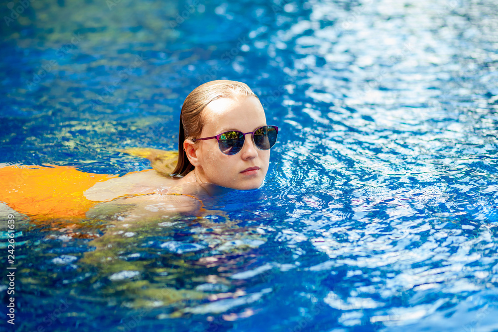 Girl with sunglasses swimming in the pool