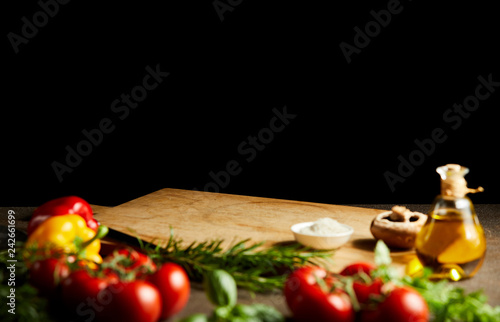 Fresh cooking ingredients around a wooden board