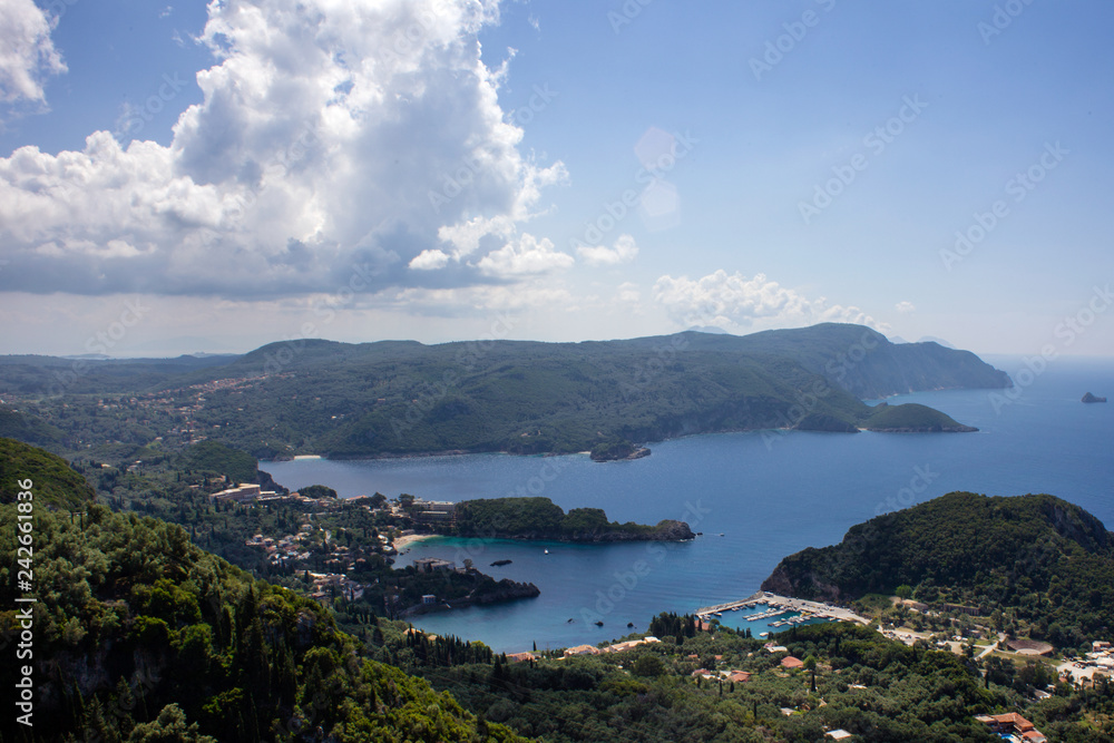 Aerial View of the Most Beautiful Bay in Corfu Greece. Landmark of Famous Mediterranean Island under a Cloudy Blue Sky. Splendid Panorama of Verdant Trees Aerial View of the Most Beautiful Bay in Corfu Greece. Landmark of Famous Mediterranean Island under a Cloudy Blue Sky. Splendid Panorama of Verdant Trees