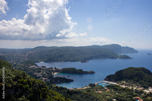 Aerial View of the Most Beautiful Bay in Corfu Greece. Landmark of Famous Mediterranean Island under a Cloudy Blue Sky. Splendid Panorama of Verdant Trees
