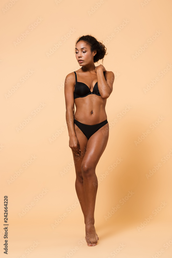 Image of sexy woman wearing black lingerie, standing isolated over beige  background Stock-Foto | Adobe Stock