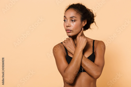 Image of young woman 20s wearing black lingerie, standing isolated over beige background