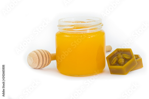 Jar of honey, wax and wooden dipper