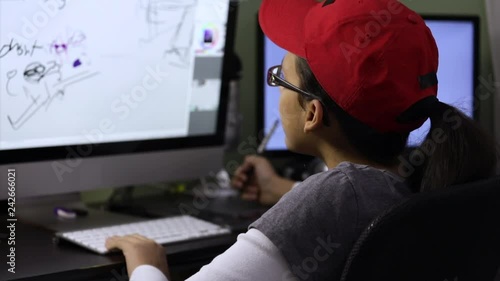 Teenage girl drawing using a ditigal tablet on the computer at her desk. photo