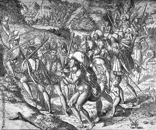 conquest of the Inca empire by Spanish Francisco Pizarro in XVI century: Spanish soldiers on the road accompanied by aborigines slaves, men and women with children, overloaded with heavy packages photo