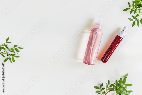 Skin care cosmetics and leaves on light background