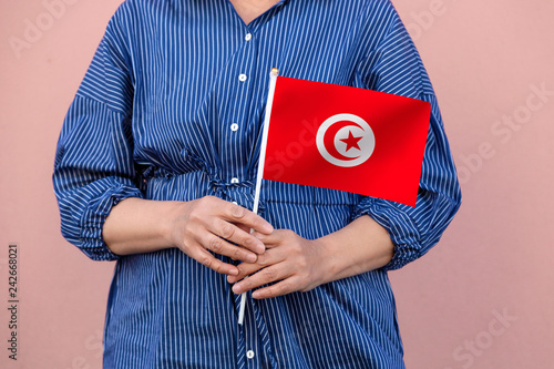 Tunisia flag. Close up of a woman's hands holding Tunisian flag.	 photo